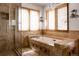 Luxurious bathroom featuring a soaking tub with tile surround, glass enclosed shower and two windows at 8626 Junco Trl, Evergreen, CO 80439