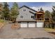 View of a gray two-story home with three garage doors and a wooden porch at 8626 Junco Trl, Evergreen, CO 80439