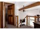 Hallway with wooden staircase and railings, featuring an open view and modern lighting fixtures at 8626 Junco Trl, Evergreen, CO 80439