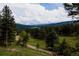 Scenic view of a green valley surrounded by tall evergreen trees under a cloudy sky at 8626 Junco Trl, Evergreen, CO 80439