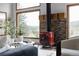 Cozy living room featuring a red wood stove, stone accent wall, and picturesque views from large windows at 8626 Junco Trl, Evergreen, CO 80439