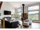 Bright living room featuring a cozy fireplace, large windows with scenic views, and comfortable seating at 8626 Junco Trl, Evergreen, CO 80439