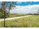 Paved walking path through prairie grass with picturesque views and community homes in the distance under blue skies at 8548 S Quatar St, Aurora, CO 80016