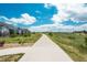 Concrete pathway runs through green grass; community homes are visible in the distance underneath bright blue skies at 8548 S Quatar St, Aurora, CO 80016
