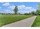 Expansive community green space featuring mature trees, walking path and neighborhood homes in the distance at 309 S 30Th Ave, Brighton, CO 80601