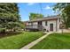 A backyard features a grassy lawn, a wooden deck, and a stone pathway leading to the back door at 1455 Hudson St, Denver, CO 80220