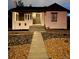 Inviting home at dusk featuring an illuminated walkway and charming front porch at 1455 Hudson St, Denver, CO 80220