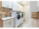 Well-equipped laundry room with modern washer and dryer, ample cabinet space, and tiled backsplash at 2800 S University Blvd # 184, Denver, CO 80210