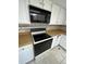 Close-up of the kitchen featuring a black stove, built-in microwave, and white cabinetry at 15983 E Loyola Dr, Aurora, CO 80013