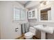 Cozy bathroom with pedestal sink, toilet, cabinet with glass doors, and window for natural lighting at 2041 W Briarwood Ave, Littleton, CO 80120