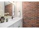 Stylish powder room featuring a brick accent wall and modern fixtures at 14890 W 58Th Pl, Golden, CO 80403