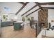 Open-concept living space with kitchen, dining, and living areas featuring vaulted ceilings and wood beams at 14890 W 58Th Pl, Golden, CO 80403