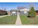 Charming single-story home with grey brick, lush lawn, and inviting front porch seating area at 373 S Locust St, Denver, CO 80224