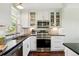 Well-lit kitchen features stainless steel appliances, white cabinets, black countertops, and hardwood flooring at 2781 Savage Rd, Elizabeth, CO 80107