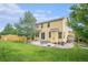 Spacious backyard with large grassy area, patio, fire pit, shed, and a yellow house at 828 Lehigh Cir, Erie, CO 80516