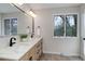 Bathroom with a double sink vanity, dark hardware, a large mirror, and a window at 2635 S Lamar Way, Lakewood, CO 80227