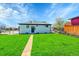 A lush backyard with manicured lawn, concrete walkway, and a white home's exterior at 7634 Navajo St, Denver, CO 80221