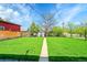 Expansive backyard with lush lawn, walkway, storage shed, and lush surrounding trees at 7634 Navajo St, Denver, CO 80221