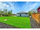 A spacious backyard featuring a green lawn, concrete walkway, and home's white siding at 7634 Navajo St, Denver, CO 80221