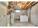 Unfinished basement featuring a utility sink, washer, dryer, water heater, and exposed ceiling at 7634 Navajo St, Denver, CO 80221