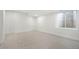 Bright basement featuring neutral carpet, baseboard, and large egress window at 3049 S Cherokee St, Englewood, CO 80110