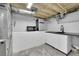 Unfinished basement kitchenette with white cabinets, sink, microwave and refrigerator at 2204 S Acoma St, Denver, CO 80223