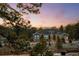 A charming grey home with a stone foundation and wooden fence surrounded by pine trees at sunset at 6001 Powell Rds, Parker, CO 80134