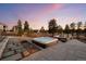 Relaxing hot tub on a stone patio with outdoor seating amidst a beautiful, landscaped backyard at twilight at 6001 Powell Rds, Parker, CO 80134