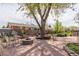 Spacious backyard with a central tree, stone patio, landscaping, and fire pit at 1313 Garden Cir, Longmont, CO 80501
