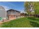 Large, grassy backyard featuring a patio, mature trees, and a charming playhouse at 1313 Garden Cir, Longmont, CO 80501