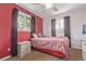 Bedroom featuring bright red accent wall, two windows, and neutral carpet at 1313 Garden Cir, Longmont, CO 80501