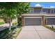 Two-story townhome features a brick facade, attached garage, and manicured lawn at 1566 S Syracuse St, Denver, CO 80231