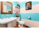 Charming powder room with pedestal sink, wooden framed mirror, and colorful striped walls at 200 Rose St, Georgetown, CO 80444