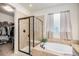Luxurious bathroom featuring a soaking tub, glass-enclosed shower, and neutral tile at 42363 Glen Abbey Dr, Elizabeth, CO 80107