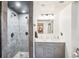 Bathroom with stone tile, shower, dual vanities, and modern lighting at 6678 S Arapahoe Dr, Littleton, CO 80120