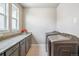 This laundry room features granite countertops, gray cabinets, stainless steel appliances, and natural light at 8299 S Kellerman, Aurora, CO 80016
