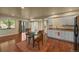 Open-plan dining area with wood flooring, a dining table, a sliding door to the backyard, and modern kitchen features at 1743 Homestead Dr, Fort Lupton, CO 80621