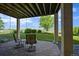 Covered patio with stone pavers, seating, and a view of the manicured backyard with mature trees at 1743 Homestead Dr, Fort Lupton, CO 80621