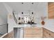Modern kitchen with sleek countertops, wood cabinets, and a view to an open-concept dining and living area at 3458 W 63Rd Ave, Denver, CO 80221