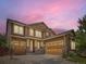 Front exterior of home with three-car garage and dusk sky background at 10045 Copenhagen St, Parker, CO 80134
