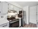 Efficient kitchen featuring white cabinets, stainless appliances and hardwood flooring at 3141 S Tamarac Dr # 206E, Denver, CO 80231