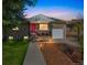Charming home exterior with a pink front door, well-lit walkway, and manicured lawn at 3241 Sheridan Blvd, Wheat Ridge, CO 80212