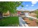 Charming brick home with a well-manicured lawn, a pink front door, and a cozy front porch at 3241 Sheridan Blvd, Wheat Ridge, CO 80212