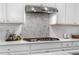 Close-up of the kitchen with white subway tile backsplash and stainless steel range hood and cooktop at 1920 Pioneer Cir, Lafayette, CO 80026