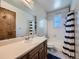This bathroom features a tub with shower, vanity, mirror and a blue and white striped shower curtain at 14665 E Stanford Pl, Aurora, CO 80015