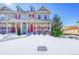 Two-story townhome with red door, snow-covered lawn, and red brick accents at 14653 E Crestridge Dr, Centennial, CO 80015