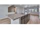 Open-concept kitchen featuring a center island with stone countertops, stainless steel appliances, and abundant natural light at 16744 W 93Rd Pl, Arvada, CO 80007