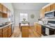 Well-lit kitchen with wooden floors, island, stainless steel appliances, and dining area at 13959 E 106Th Ave, Commerce City, CO 80022
