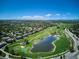 Stunning aerial view of a golf course community with a pond and lush green fairways under a bright blue sky at 9545 Grand Cypress Cv, Lone Tree, CO 80124