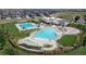 Aerial view of community pool area featuring multiple pools, seating, and playground at 148 Baler Ct, Brighton, CO 80601